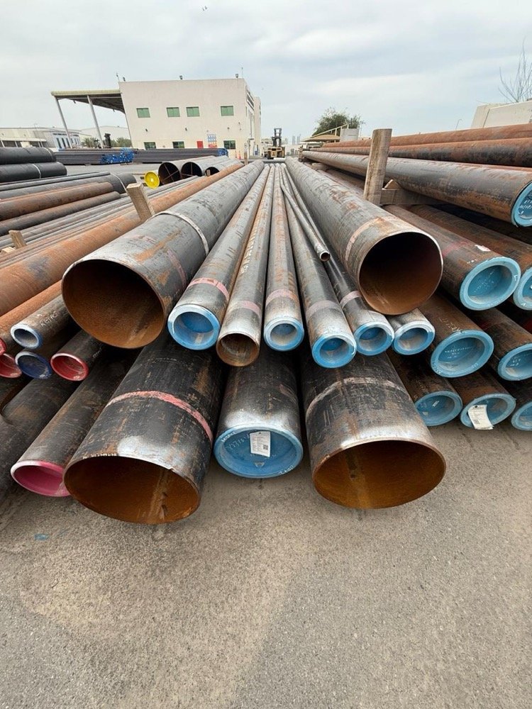 Coiled steel line pipe stacked in an oilfield equipment yard